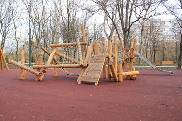 Outdoor modern children wooden playground in a public park of city.  Eco-friendly lifestyle rest and childhood concept of safety environmentally infrastructure for kids.