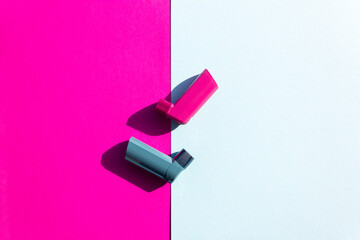 Creative asthma concept. Blue and pink asthma inhalers on a blue and pink background. Flat lay....