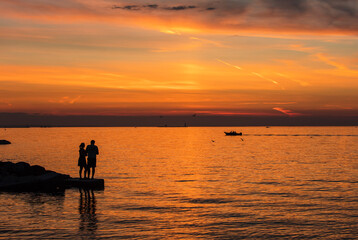 Naklejka na ściany i meble Couple enjoys a romantic sunset view in Collingwood waterfront park in summer