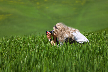 Blonde woman photographer taking landscape photographs in Tuscany, Italy, Europe