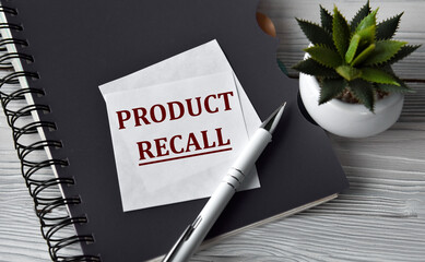 PRODUCT RECALL - words in a white notebook against the background of a black notebook with a pen