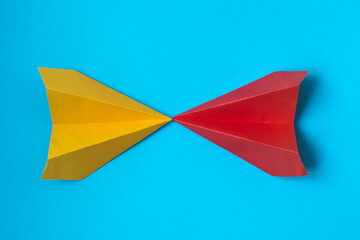 multicolored paper planes on a blue background. The concept of leadership, teamwork and courage.