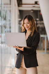 Fototapeta premium Asian businesswoman in formal suit in office happy and cheerful during using smartphone and working