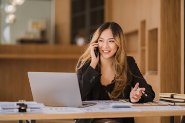 Asian businesswoman in formal suit in office happy and cheerful during using smartphone and working