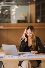 Asian businesswoman in formal suit in office happy and cheerful during using smartphone and working