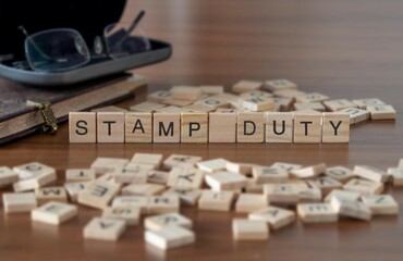 stamp duty word or concept represented by wooden letter tiles on a wooden table with glasses and a book