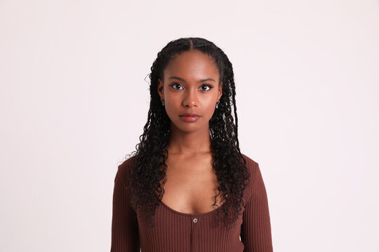 Thoughtful dark skinned young woman poses indoor and looks at the camera.