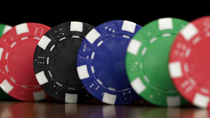 Naklejka premium Poker chips stand in a row on a black background, a Domino effect. Playing poker chips are on the table, a symbol of casino