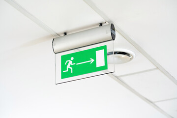 Modern green emergency exit route door arrow sign on the ceiling, object detail, closeup, nobody....
