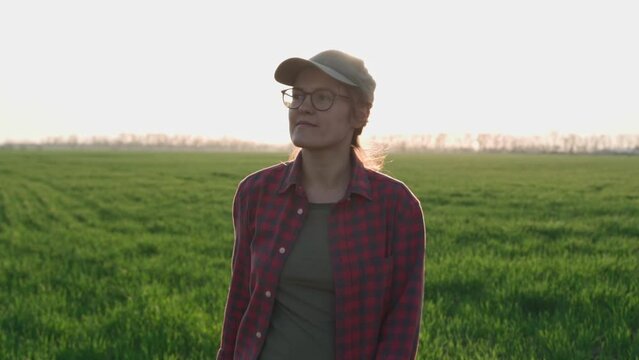 Farmer woman inspects the fields. Portrait on girl agronomist. Agriculture. Organic smart farming industry. Close up of Caucasian good looking Young woman smiling and walks through the green field