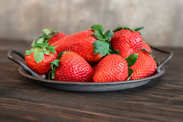 Background with close-up fresh strawberries at steel tray on wooden table. Tray with whole ripe strawberries
