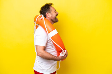 Lifeguard middle age man isolated on yellow background laughing in lateral position
