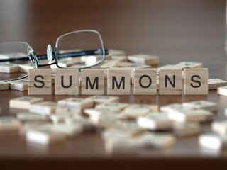 summons word or concept represented by wooden letter tiles on a wooden table with glasses and a book