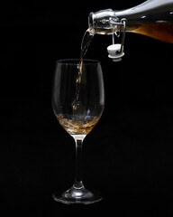 A glass and spilling wine from a bottle on a black background. Close-up