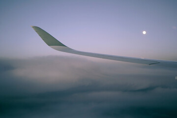 Fototapeta na wymiar Moon, clouds and the airplane wing, view from the passenger's window.