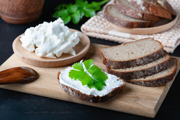 Home made bread on a wooden cutting board with curd cheese and ricotta