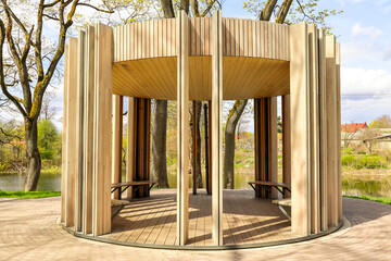 A round wooden gazebo in a public garden park