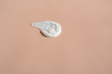 White smear of cosmetic cream on a beige background. Creamy foundation texture isolated. Smear of face cream. Close up of cream texture
