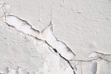 Texture of an old concrete light gray painted wall with cracks close up