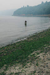 Seattle, WA, USA - August 20, 2018: BNSF freight train traveling through Carkeek Park during a smoky evening with single man fishing in puget sound