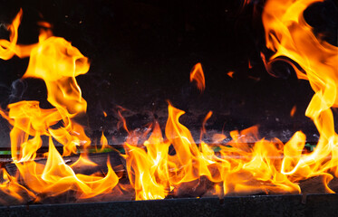 Bright orange flashes of fire from a bonfire on coals