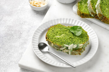 Piece of cake with spinach on white board with tea in a cup. Green pie with almond.