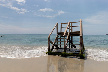 Old and rustic mossy wooden stairs at Colombian Rodadero Santa marta city beach with caribbean sea and blue sky at background