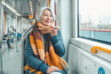 Senior woman send message with a mobile phone in a train
