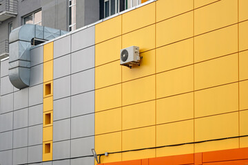 Ventilated yellow building facade of metal cassettes. Ventilation pipe and air conditioning on a...