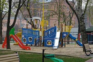 Empty playground in the city park. Playground in the shape of a ship, with slides and stairs....