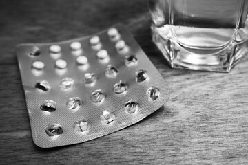 Open pack of pills in a blister and a glass close-up shot