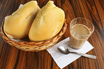 Bread basket with latte glass on rustic table.