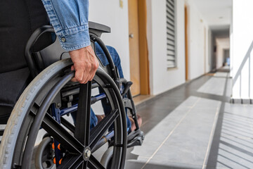 MAN WITH PHYSICAL DISABILITY USING A WHEELCHAIR IN A CORRIDOR. CONCEPTUAL IMAGE OF INCLUSION, INTEGRATION FOR PEOPLE WITH DISABILITIES AND REMOVE BARRIERS. - obrazy, fototapety, plakaty