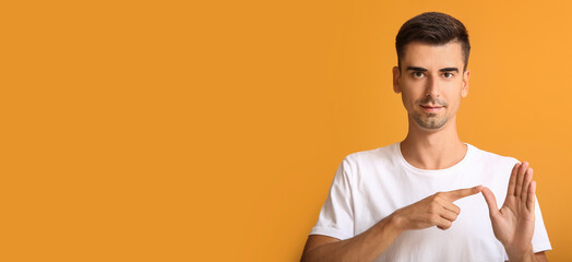 Young deaf mute man using sign language on orange background with space for text