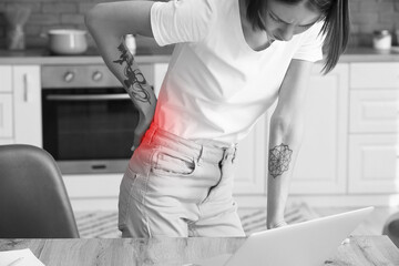 Young woman feeling back pain in kitchen