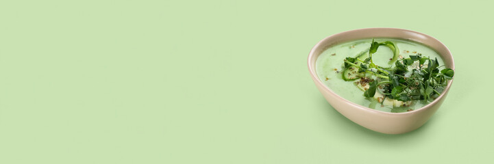 Bowl of tasty gazpacho on light green background with space for text