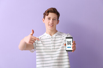 Young guy pointing at smartphone with QR code on screen against lilac background