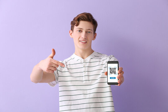Young guy pointing at smartphone with QR code on screen against lilac background