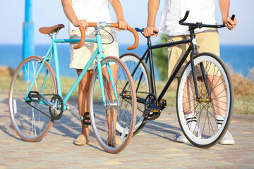 Fototapeta na wymiar Mature couple with bicycles walking along sea shore on summer day