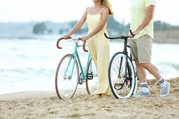 Obraz premium Mature couple with bicycles walking along sea beach on summer day