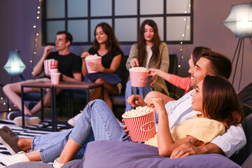 Group of friends watching movie at home in evening