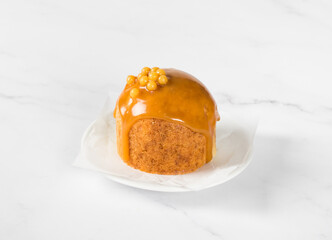 Caramel Honey cake with icing, decorated with mini candy dragees, on a plate. White background