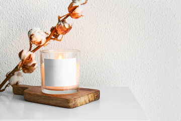 Holder with burning candle and cotton branch on table, closeup