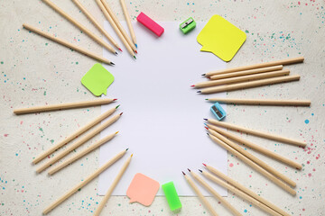 Colorful pencils, blank paper sheet and stationery on light grunge background
