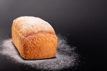 close up french lean bread with flour on a black background. Concept recipe of handmade bread