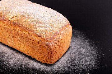 close up french lean bread with flour on a black background. Concept recipe of handmade bread