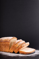close up sliced french lean bread with flour on a black background. Concept recipe of handmade bread