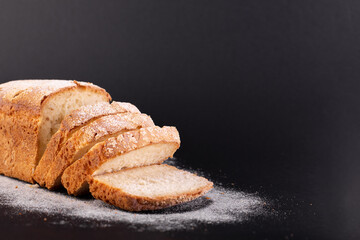 close up sliced french lean bread with flour on a black background. Concept recipe of handmade bread