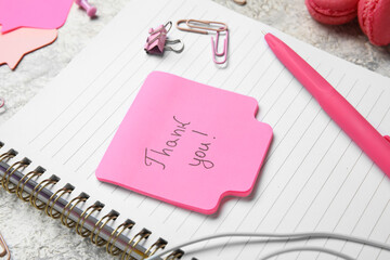 Sticky note with text THANK YOU, pen, clips and notebook on grunge background, closeup