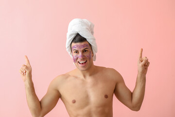 Handsome man with glitter mask and towel on pink background